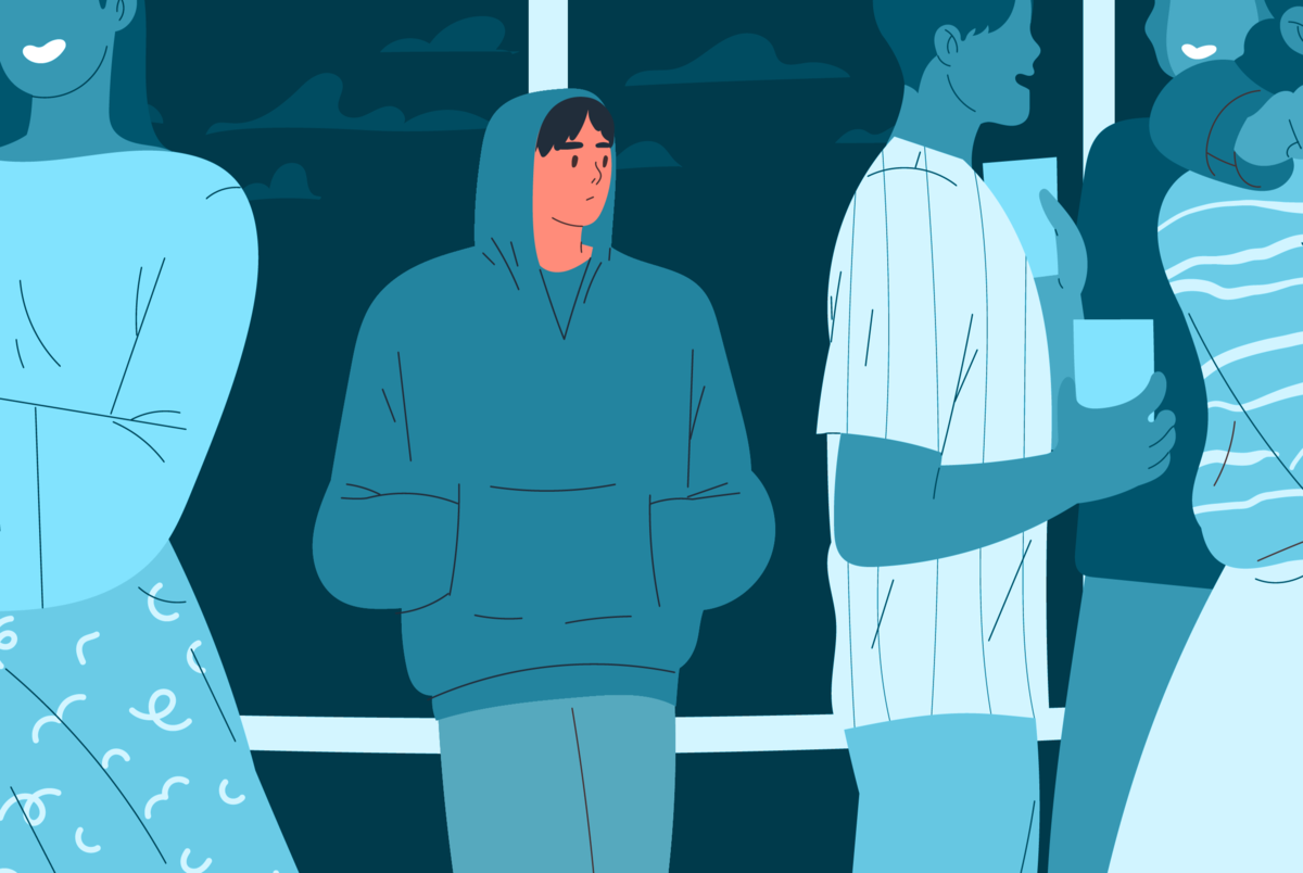 Na obrazku widzimy osobę, która stoi samotnie przy grupie innych osób.
